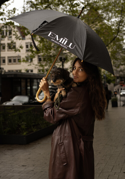 Eine Damie mit Hund auf dem Arm und Regenschirm in der Hand