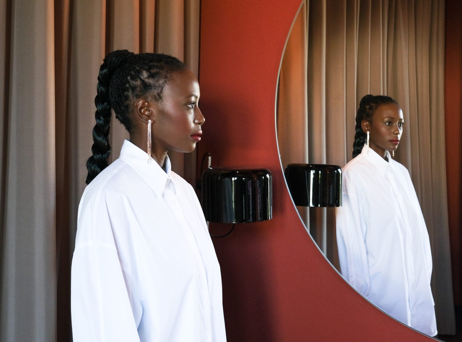 Women in white Shirt in a red room facing the mirror