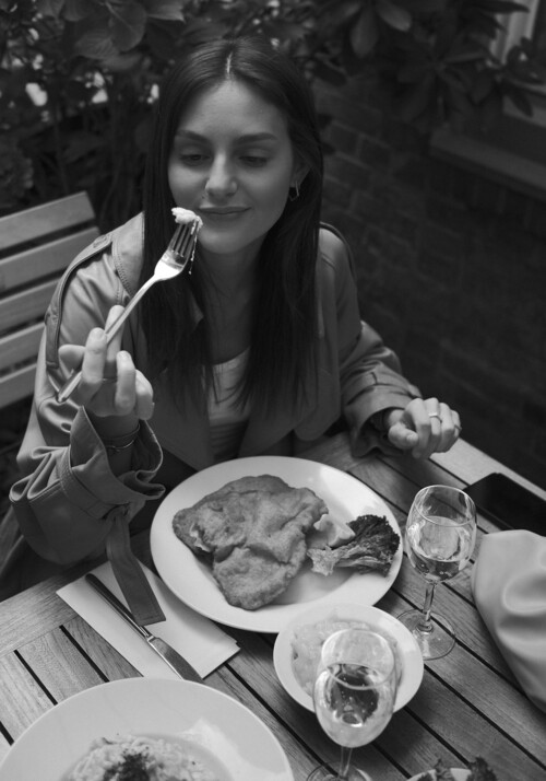 Black and white picture of a women eating a schnitzel