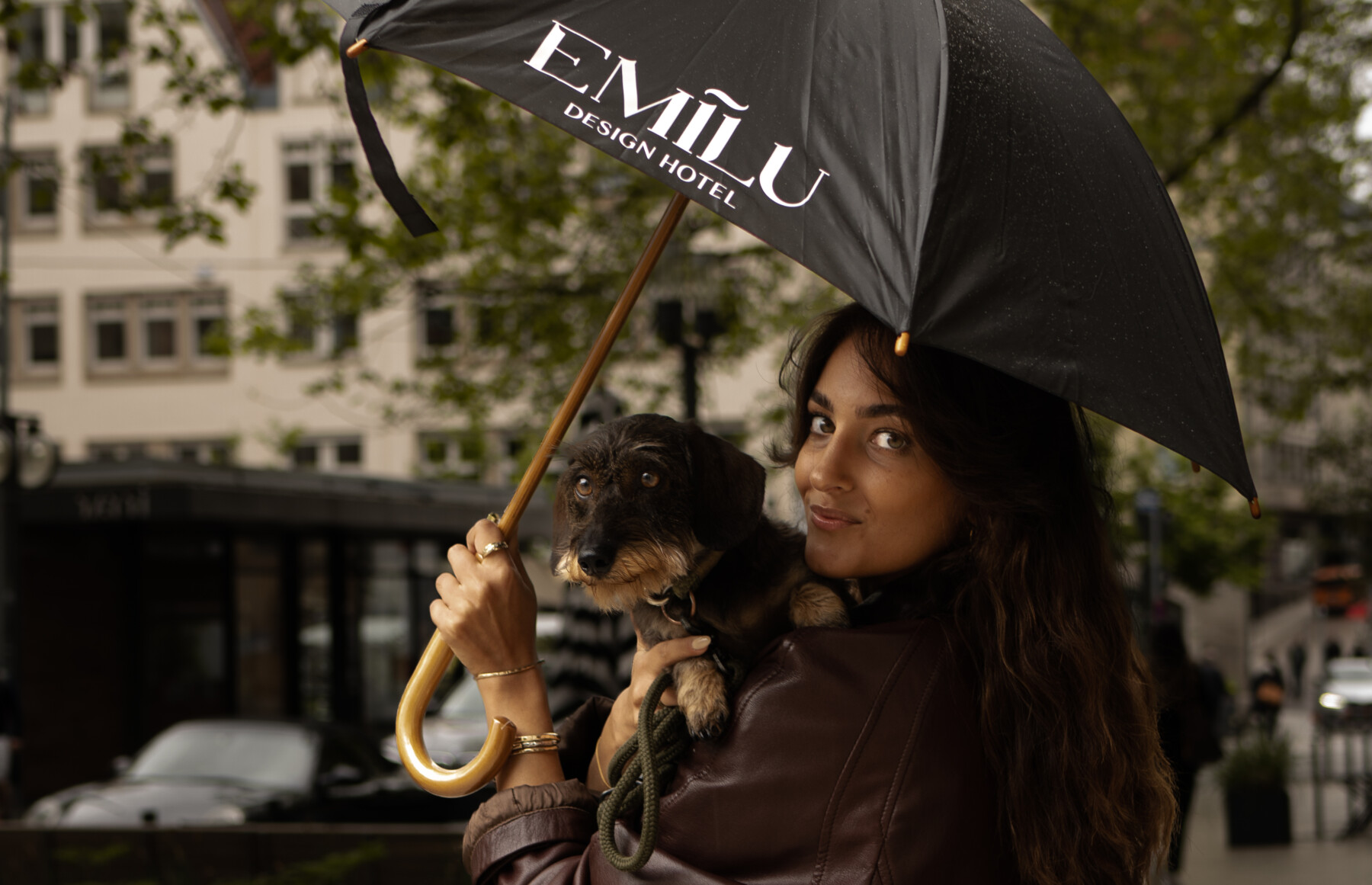 Eine Damie mit Hund auf dem Arm und Regenschirm in der Hand