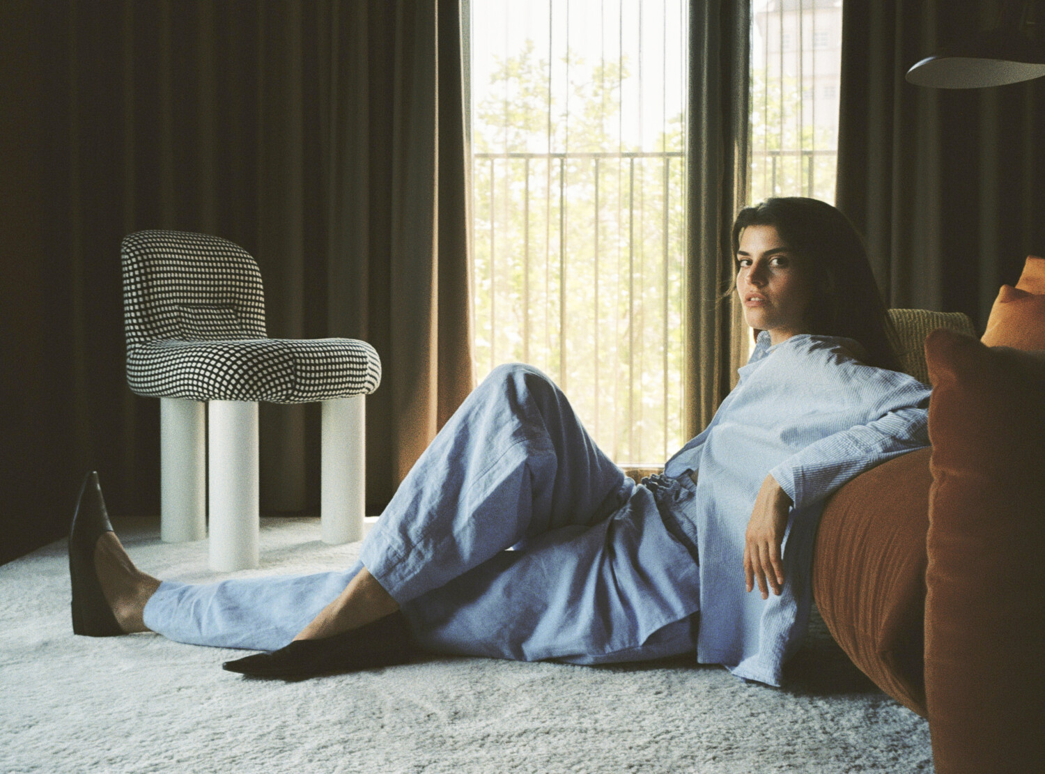 Frau in blauem Pyjama lehnt an eine rote Couch