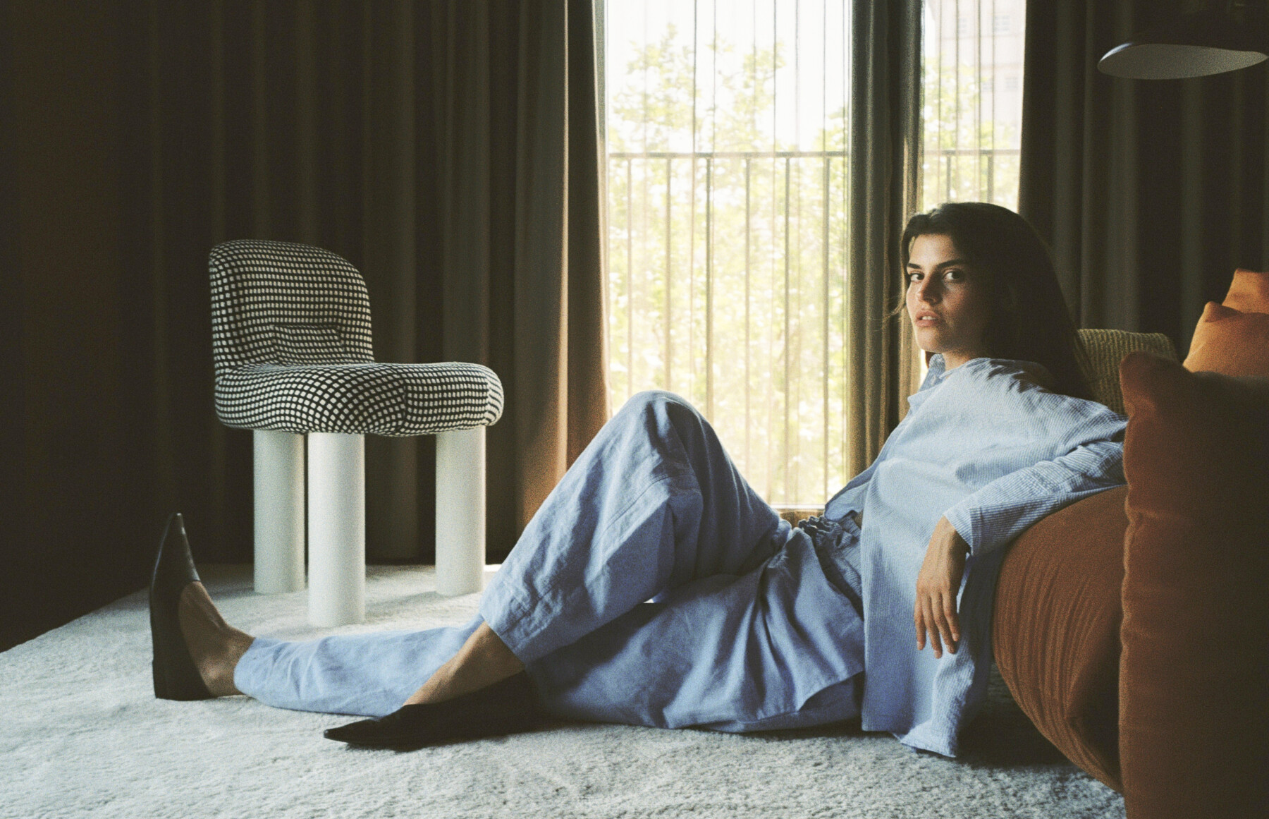 Women in a blue Pyjama leaning on a red couch