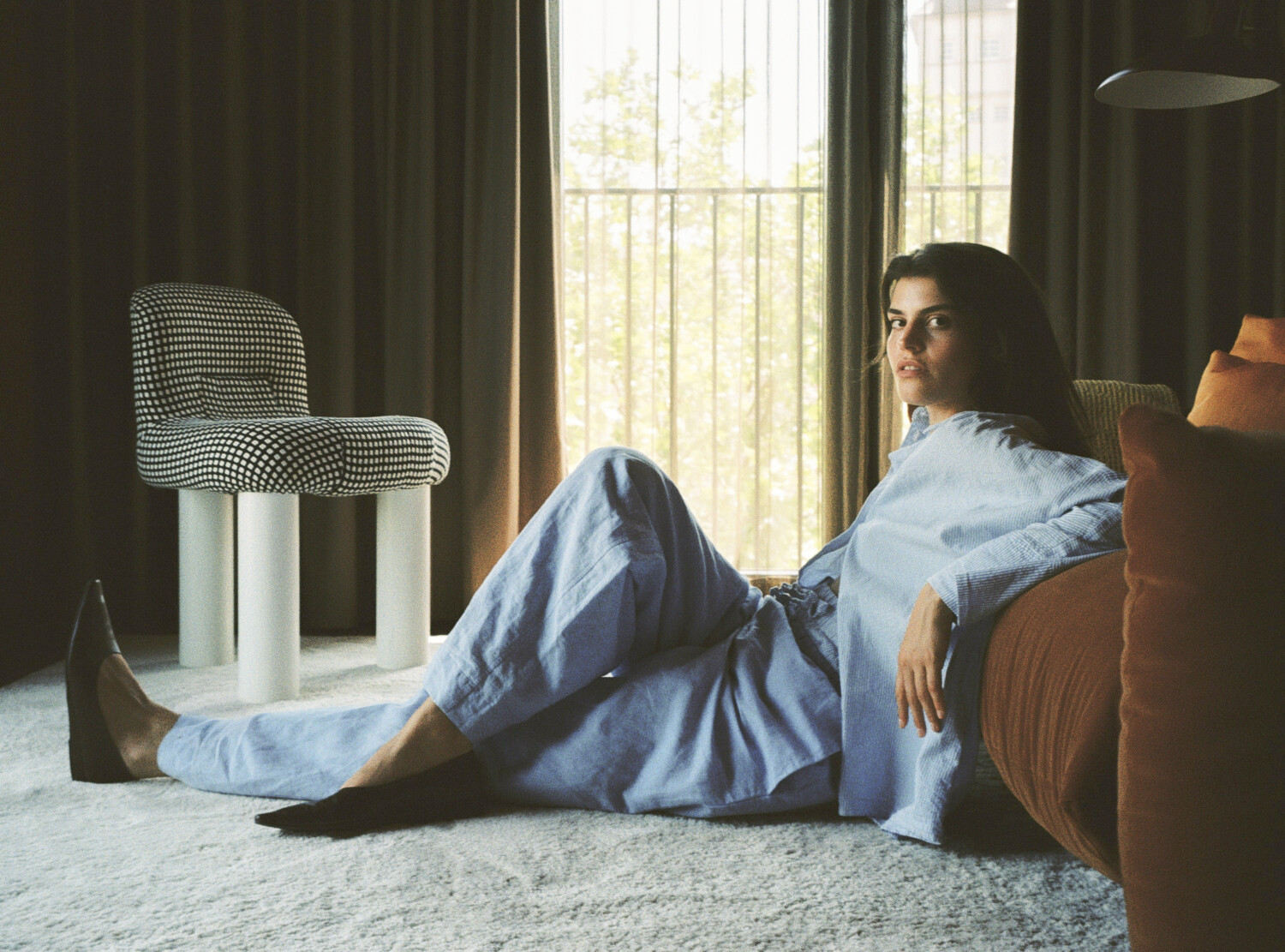 Women in a blue pyjama leaning on a red couch